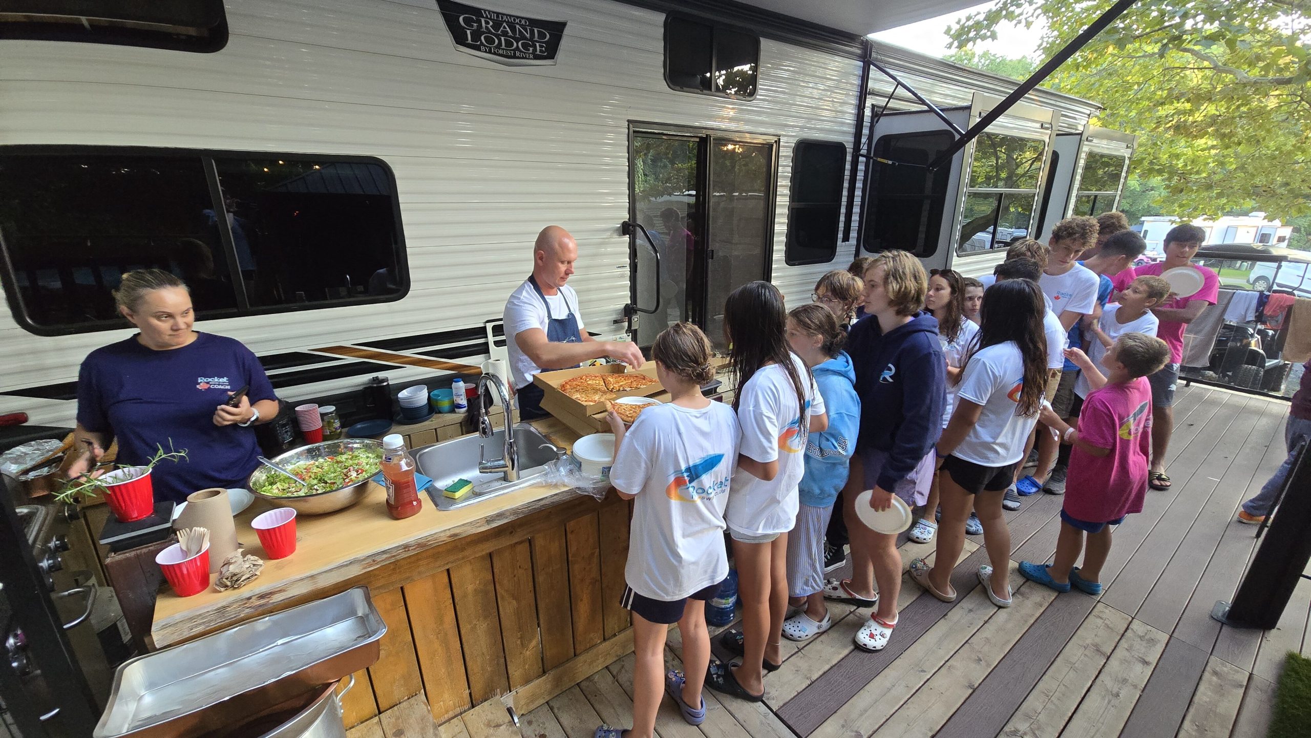 RocketSwim swimmers and coaches sharing a meal at summer camp in 2026